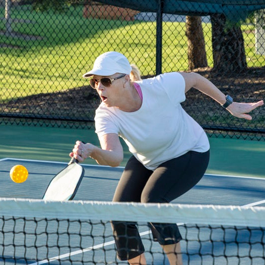 Senior players enjoying a game of pickleball on a sunny day.